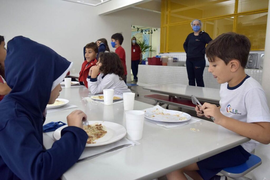 Crianças fazendo refeição no refeitório de escola infantil