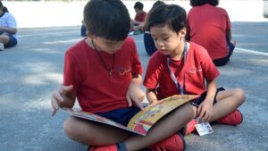 Duas crianças fazendo a leitura de um livro.